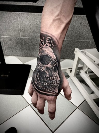 Tattoo eines Schädels auf der Hand eines Menschen, detailreich und schwarz-weiß.