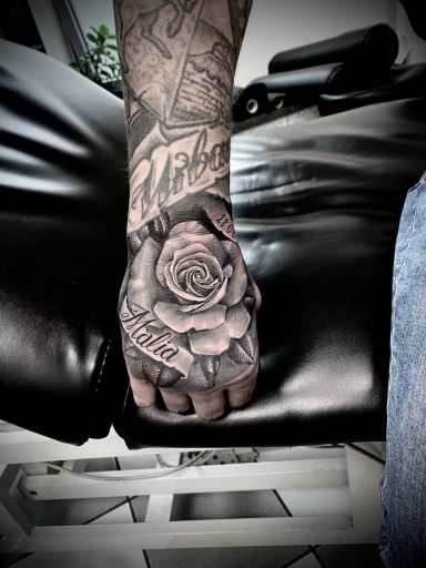 Tattooed Hand mit einer detaillierten Rose auf dem Handrücken.