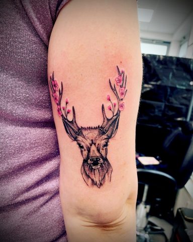 Tattoo eines Rehs mit kunstvollen, rosa gezeichneten Geweihverzierungen.