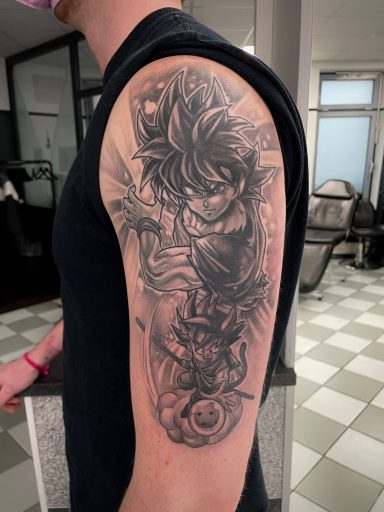 Tattoo eines Charakters mit dynamischen Linien und Schattierungen auf einem Oberarm.