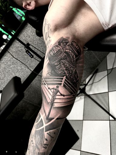 Tattoo auf dem Arm mit geometrischen Mustern und einer stilisierten Klinge.