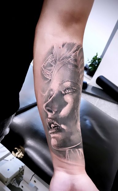 Schwarz-weißer Arm-Tattoo mit einer stilisierten Frauenansicht und feinen Details.