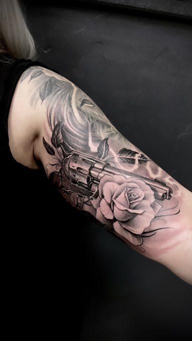 Schwarz-weißer Tattooschmuck auf einem Arm mit einer Rose und ornamentalen Mustern.