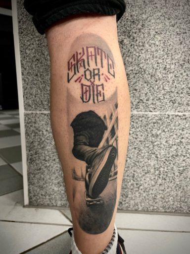 Tattoo eines Skaters mit dem Text "Skate or Die" auf dem Unterschenkel.