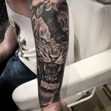 Tattoo eines brüllenden Tigers auf dem Unterarm eines Personen.