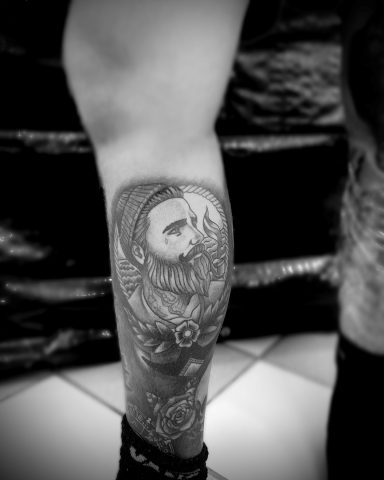 Schwarz-weiß-Tattoomotiv auf dem Bein, zeigt eine detailreiche Portraitdarstellung.