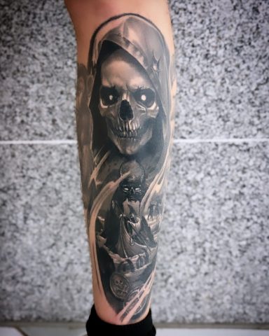 Schwarz-weißer Tattoo mit einem Skelett und einer mystischen Figur auf dem Unterschenkel.