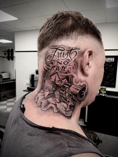 Tattoo auf der linken Kopfseite mit grafischen Motiven und Schriftzügen.