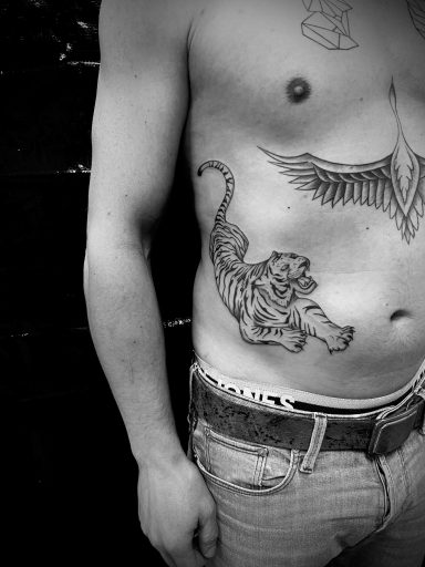 Tattoo eines Löwen auf der linken Seite eines nackten Oberkörpers.