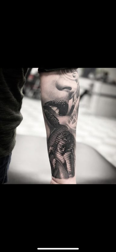 Schwarzes Tattoo auf dem Unterarm, das eine dramatische Figur und Details zeigt.